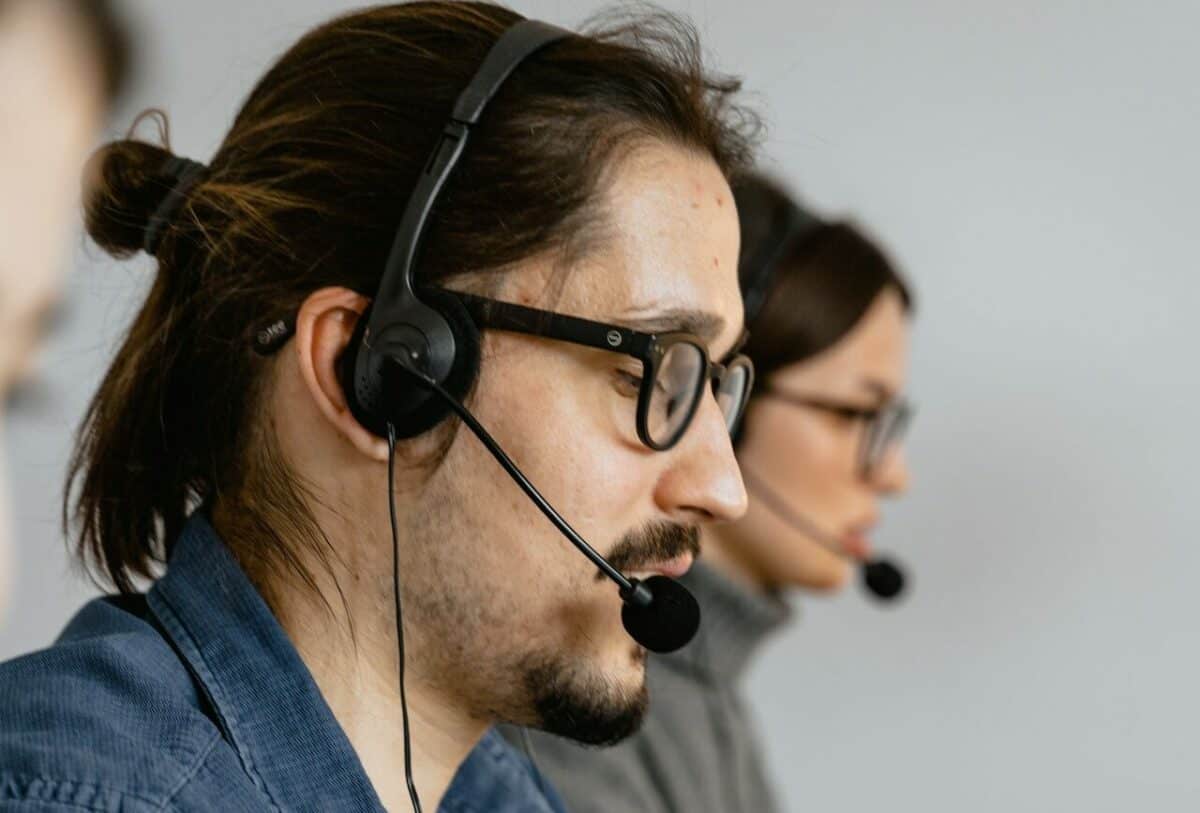 Two individuals in glasses and headsets working at a call center for outsourced IT services, focusing intently on their tasks.