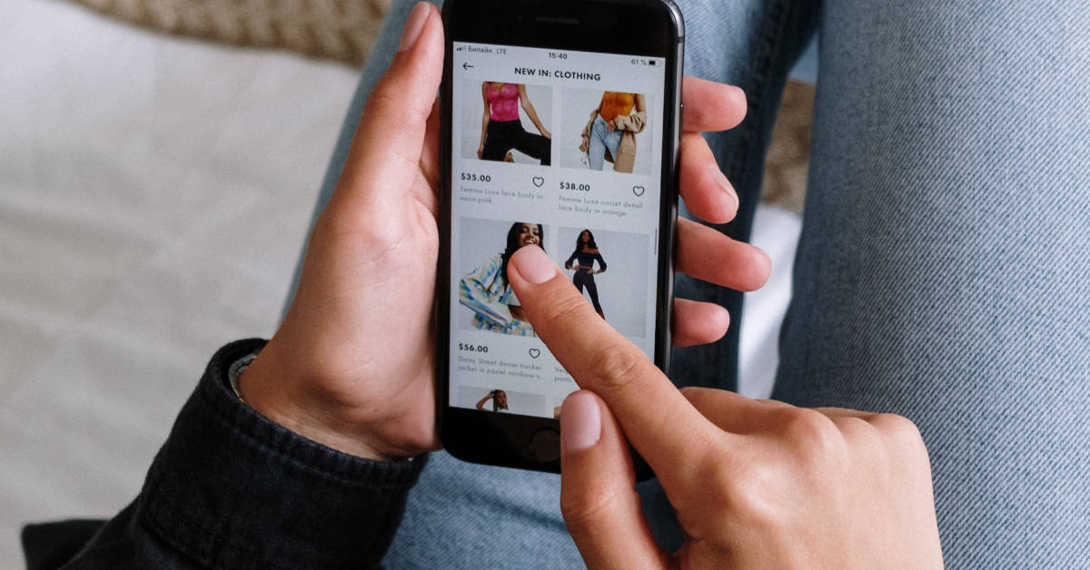 Person browsing an e-commerce clothing store on a smartphone, displaying various outfits with prices and the psychology of color in product presentation visible.