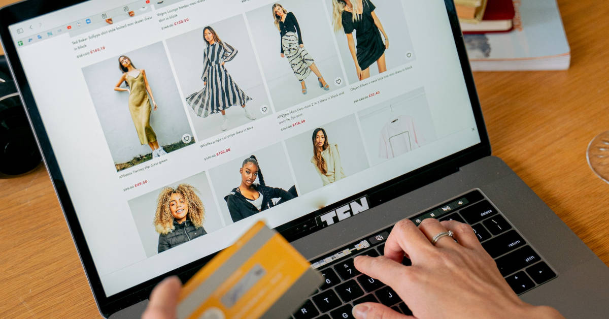 Person shopping online for clothing on a laptop, holding a credit card, with multiple images of women's dresses displayed on the screen, exemplifying e-commerce success.