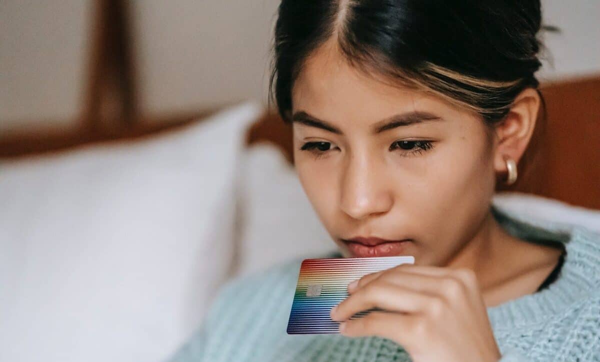 A person holds a colorful card, perhaps contemplating over payment solutions.