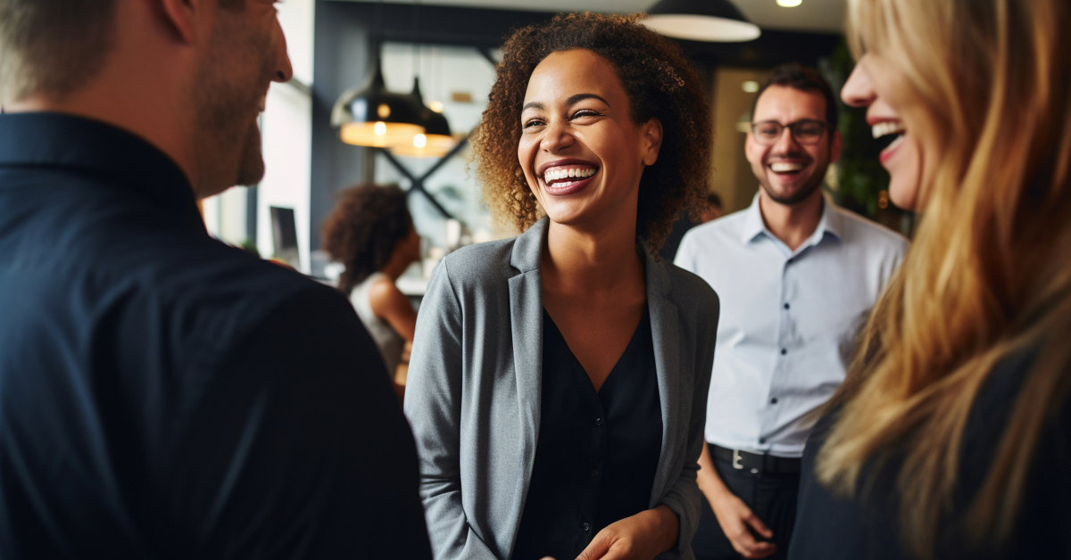 A group of people engaging in conversation and laughing in an indoor setting, perhaps discussing ways to unveil the value of performance bonds that benefit businesses.