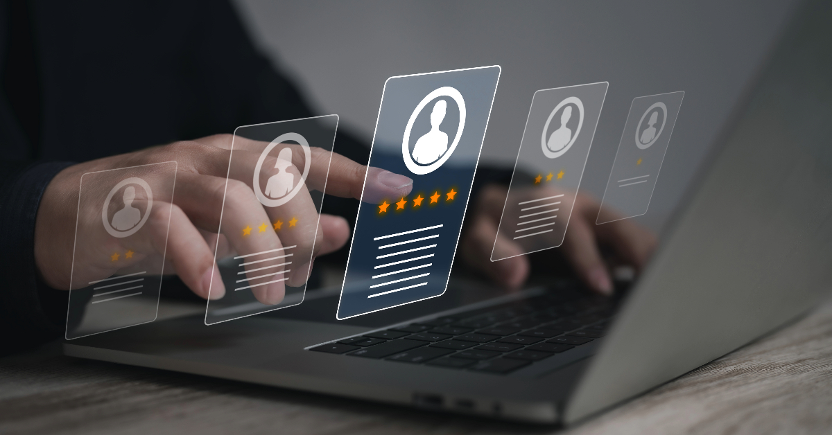 A person using a laptop with holographic images of profiles and star ratings hovering over the keyboard, possibly indicating HR software evaluations or online reviews for businesses.