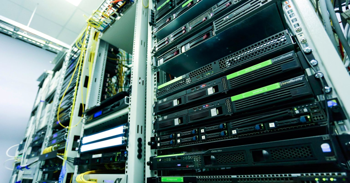 A close-up view of a server room with multiple server racks filled with network hardware, cabling, and advanced database technologies.