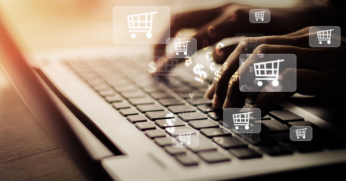 Hands typing on a laptop keyboard with shopping cart icons and currency symbols overlayed, indicating the advantages and disadvantages of e-commerce in entrepreneurship.