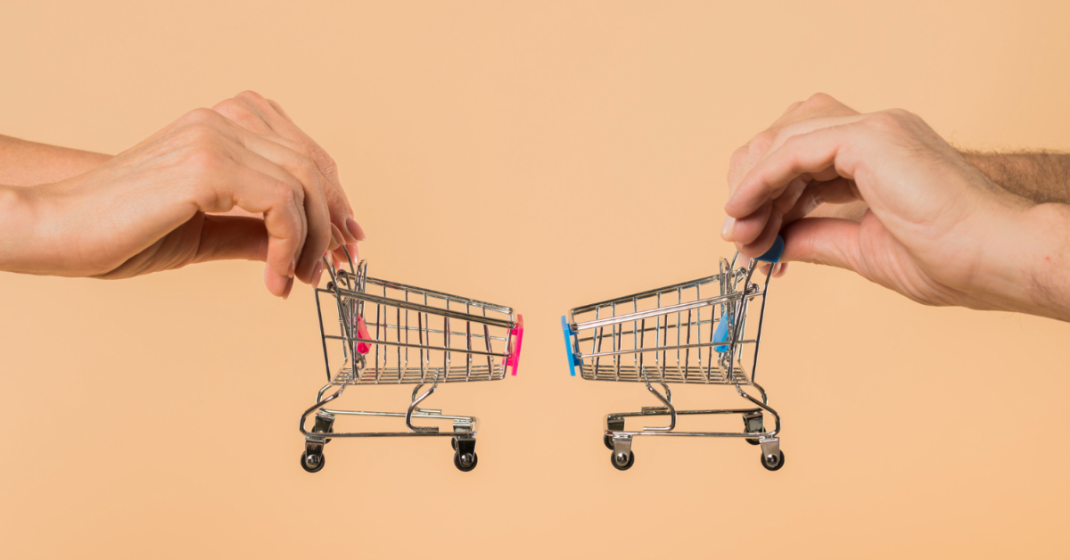 Two hands, each holding a miniature shopping cart with pink and blue handles, are positioned against a beige background, symbolizing the importance of ecommerce optimization to avoid abandoned carts.