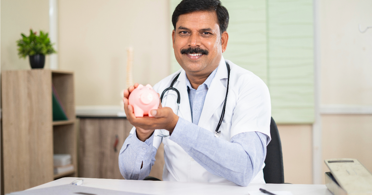 A smiling doctor in a white coat and stethoscope holds a pink piggy bank in an office setting, symbolizing the importance of planning for medical costs.