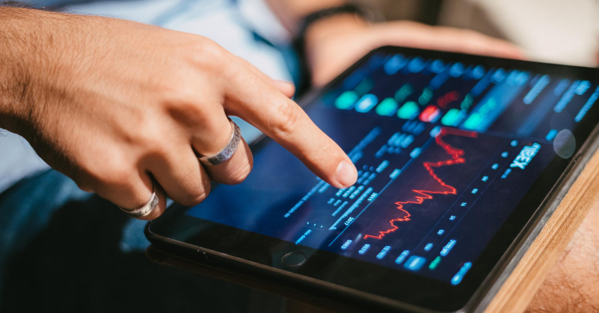 A person analyzing stock market data on a tablet, finger pointing at a red downward trend line, possibly speculating how cryptocurrency slots might influence their investments in the United Kingdom.