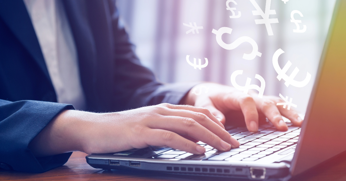 A person in a suit is typing on a laptop, accessing SaaS solutions with various currency symbols floating above the keyboard.