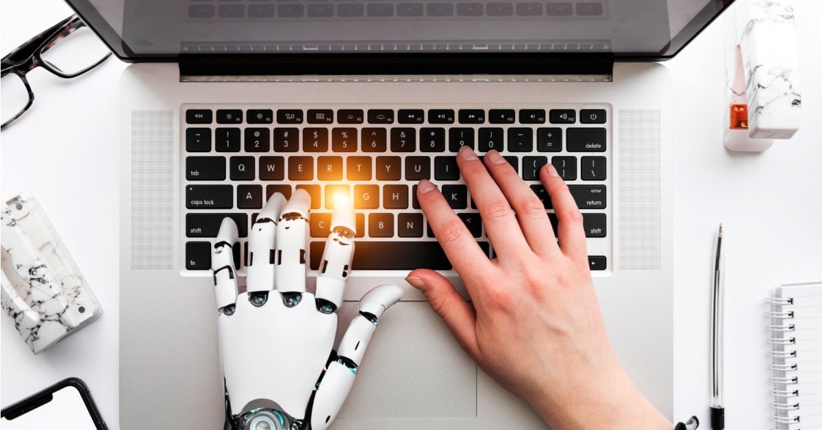 Human and robotic hands are typing on a laptop keyboard, effortlessly crafting high-quality content using an AI writing tool.