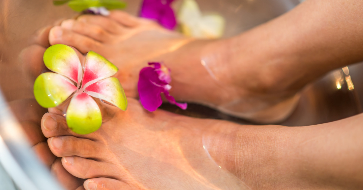 A serene close-up of two feet in a water basin with floating flowers, perfect to promote on social media for those seeking beautiful feet pics.