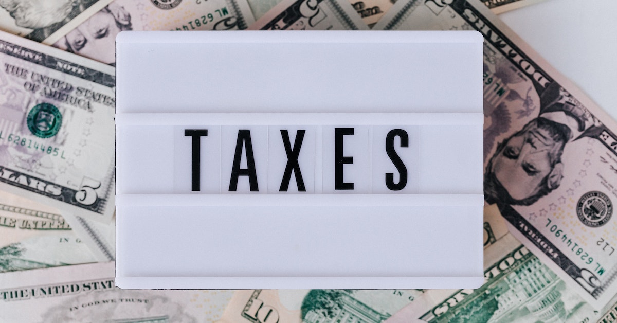 A lightbox with the word "TAXES" sits atop a scattered spread of various US dollar bills, serving as a stern reminder of the tax mistakes that can impact your business.