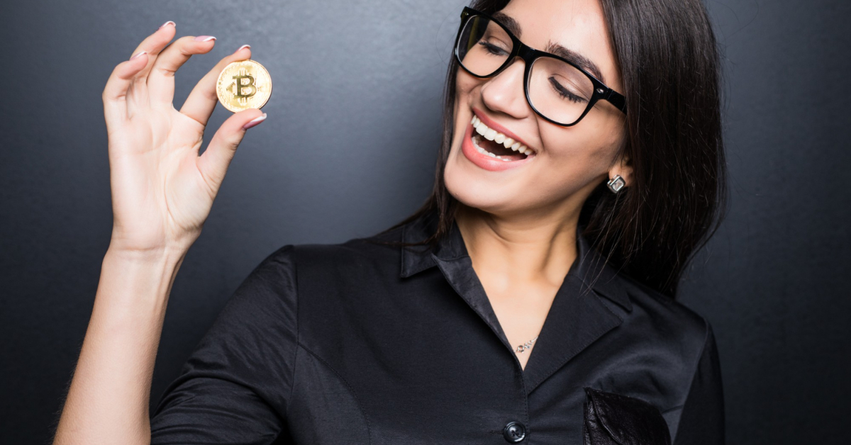 A person wearing glasses and a black shirt holds a Bitcoin coin, smiling and looking at it with crypto insights, envisioning a promising future.