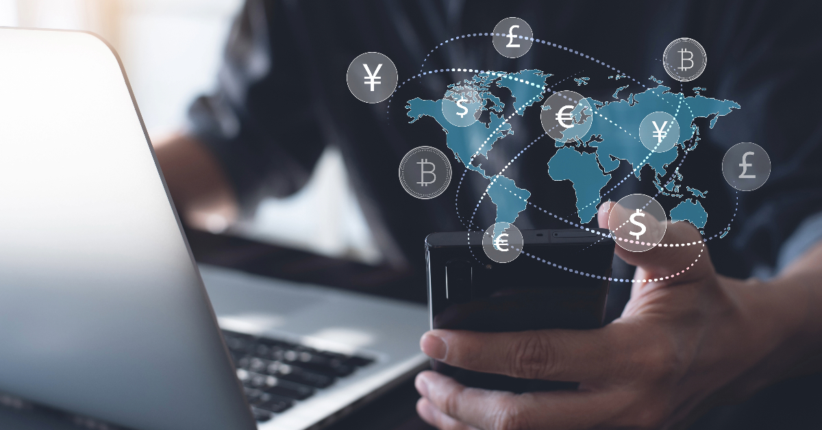 A person using a smartphone and laptop, with a digital overlay of a world map and various global currencies such as Dollar, Euro, yen, and bitcoin, representing global financial connections.