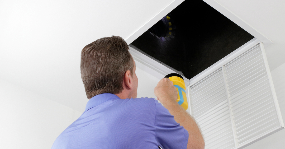 A man using a vacuum to clean air ducts in the Lowcountry.