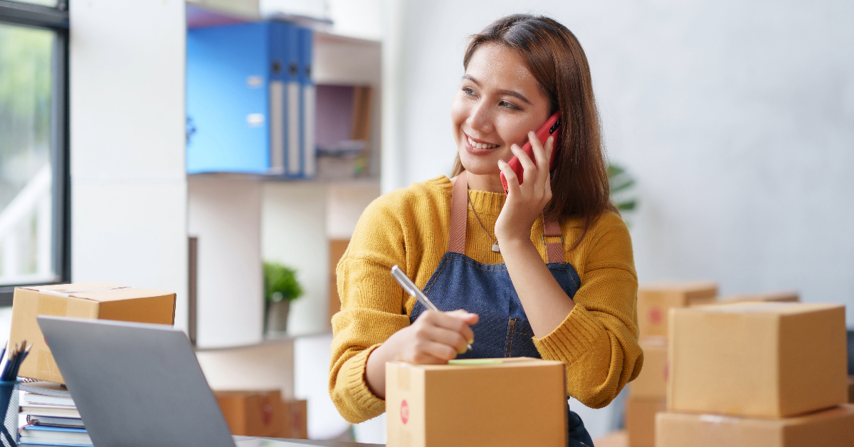 A woman engaged in social listening while sitting at a desk with boxes.