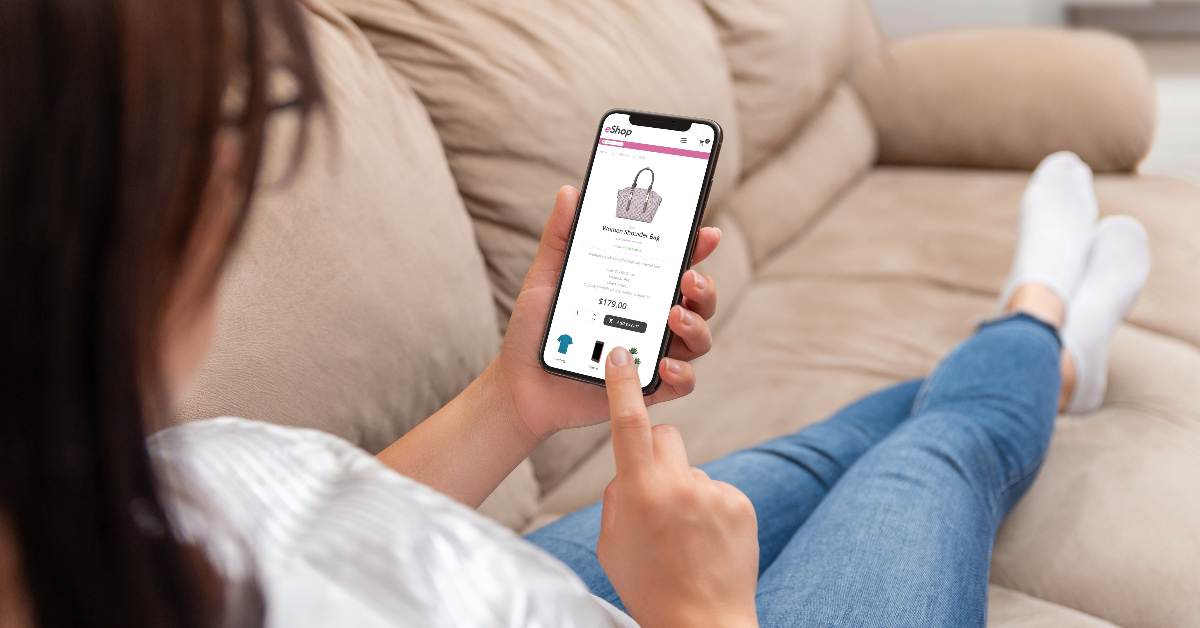 Person lounging on a beige sofa, enjoying a personalized shopping experience for a handbag on their smartphone.
