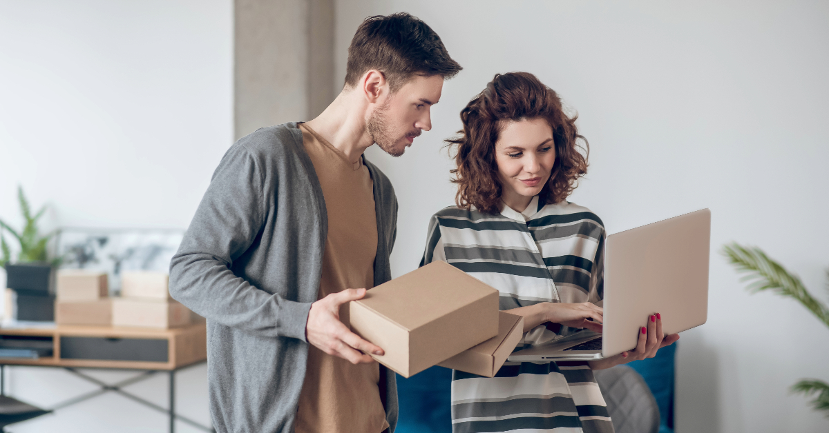 A couple shopping on Amazon via e-commerce, reviewing an advertisement on their laptop in their new home.