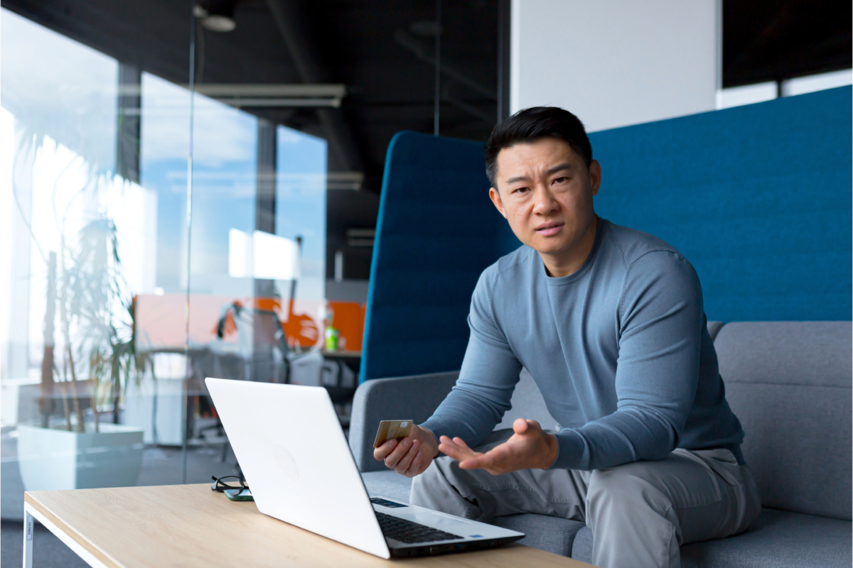 A man sitting on a couch browsing trends and statistics with a laptop.