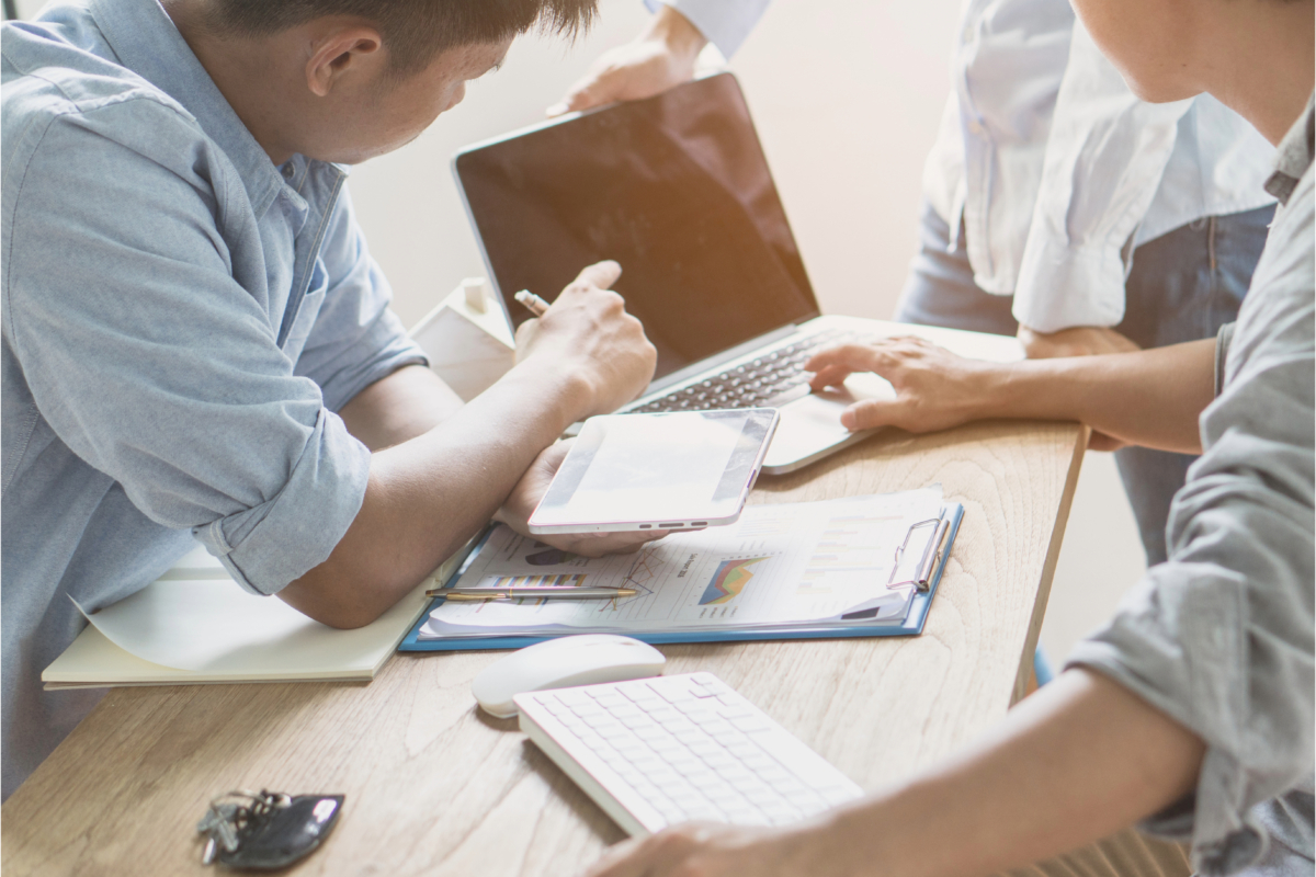 A group of business people working on a laptop at a desk, displaying common signs of teamwork and collaboration.