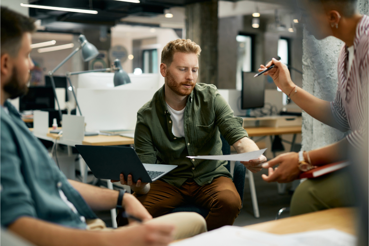A group of people conducting market research while sitting around a table in an office for starting a business.