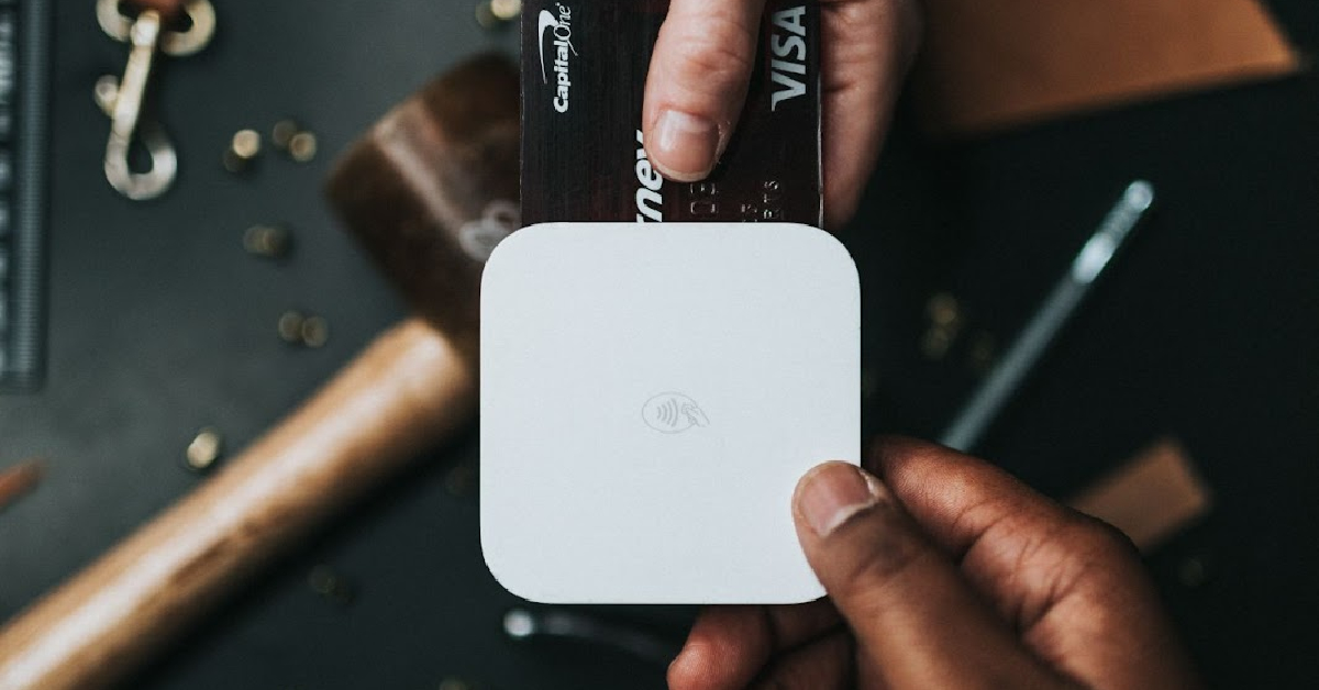 A person is holding a credit card while sitting at a table, making an online purchase as part of their E-commerce business marketing strategy for Black Friday.