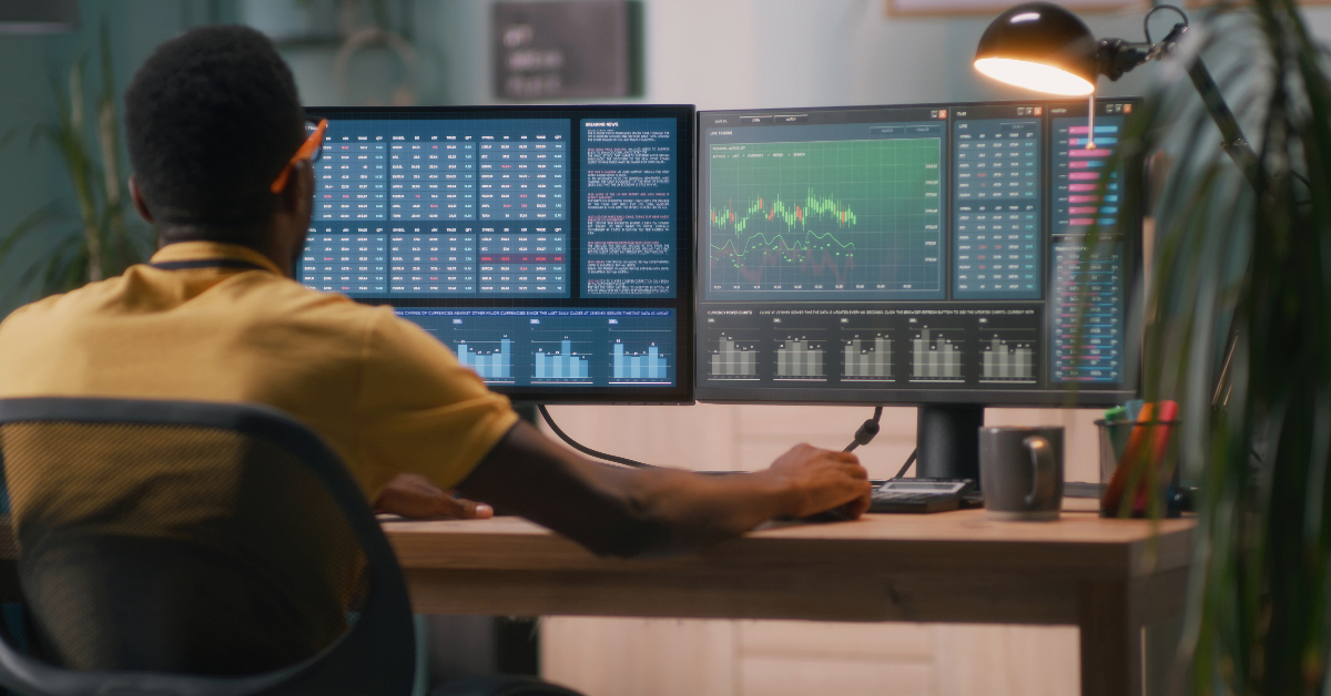 Person sitting at desk, analyzing financial data on two monitors displaying charts and spreadsheets, highlighting key features of both on-chain and off-chain transactions.