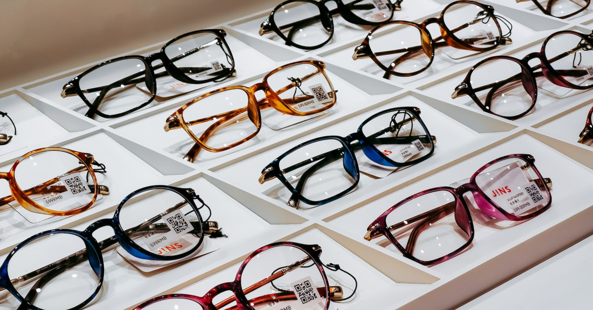 A variety of eyeglasses with different frame styles and colors displayed in rows on white trays, perfect for your Eyeglasses E-commerce store. Each pair has a small tag attached to them, ideal for maximizing online presence through detailed product listings.