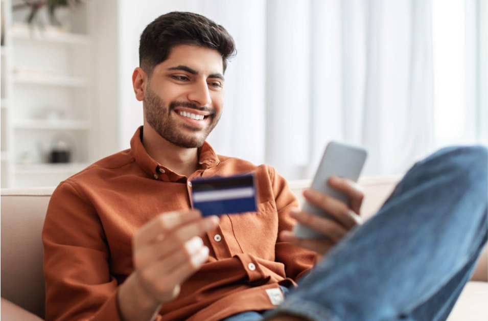 A man enjoying the benefits of a credit card while sitting on the couch.