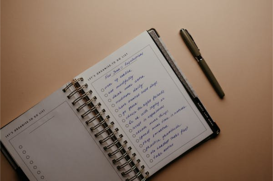 Open notebook with a handwritten to-do list and a pen placed beside it on a beige surface. Tasks include "buy groceries," "reply to emails," and "exercise." This simple setup is perfect for anyone looking to improve productivity without relying on to-do list apps.