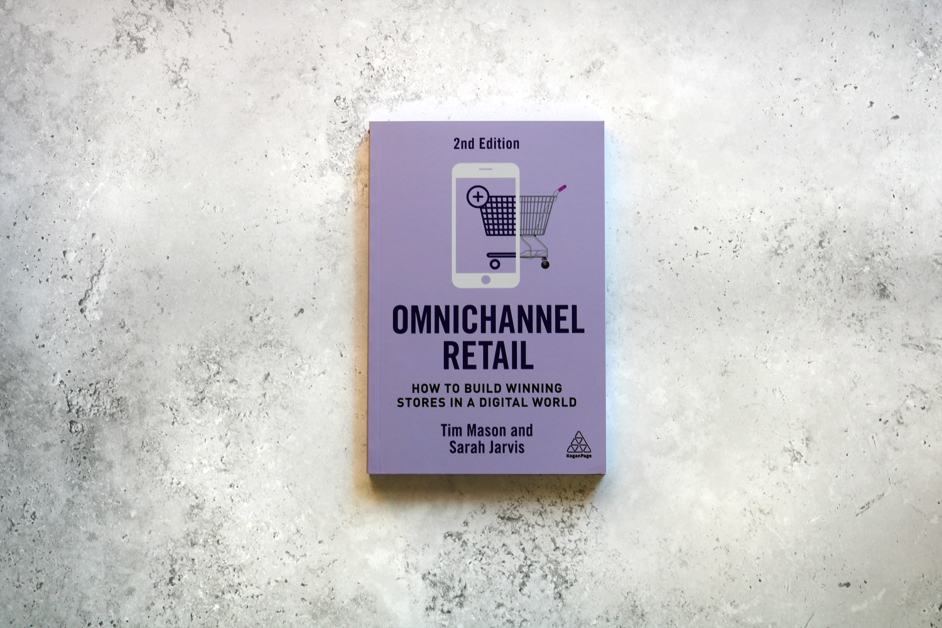 A book titled "Omnichannel Retail: How to Build Winning Stores in a Digital World" 2nd edition by Tim Mason and Sarah Jarvis, on a gray textured surface.