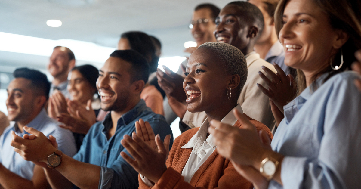 A group of business people clapping in a conference room.