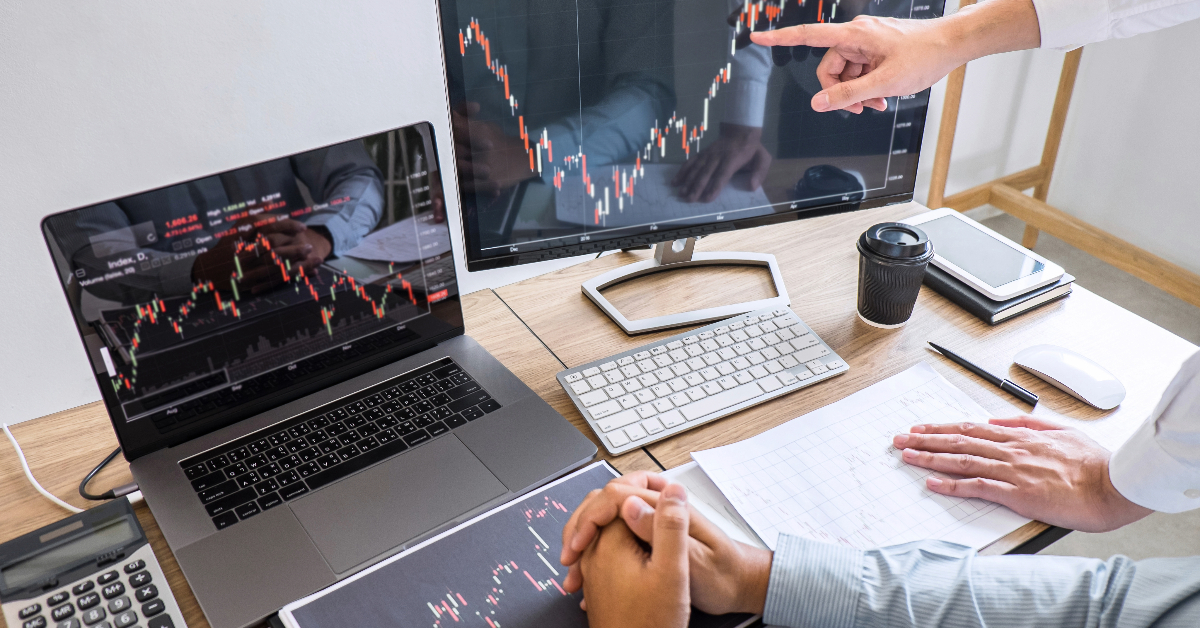 Two people, potentially forex brokers, sitting at a desk and attentively analyzing a stock chart for lead generation purposes.
