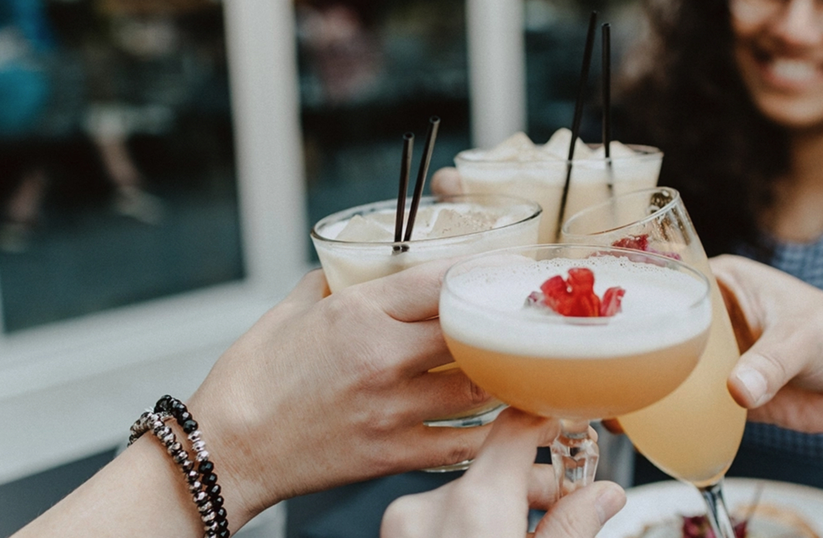 A group of friends indulging in cocktails at a restaurant, embracing the essence of alcohol and enhancing creator campaigns through influencer marketing.