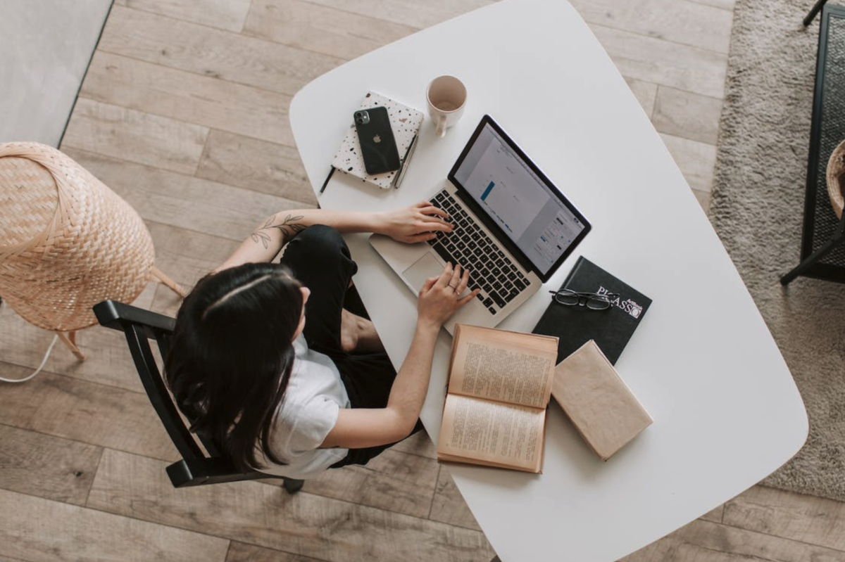 A woman using digital media on a laptop in a living room, potentially impacting children's reading habits.