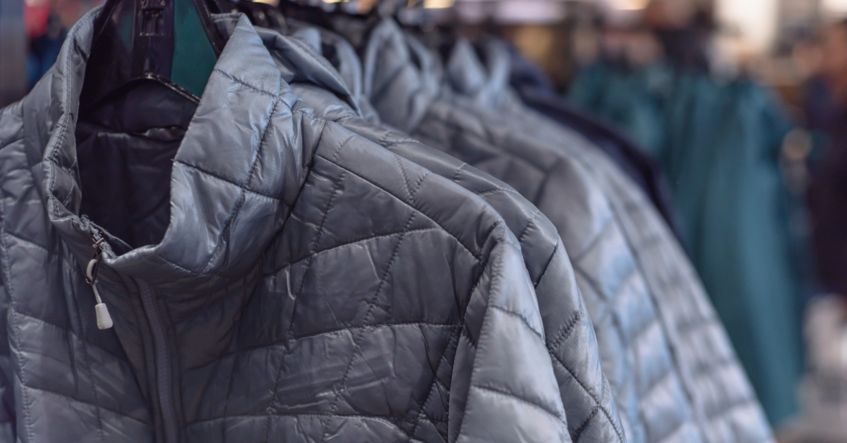 A row of sustainable outdoor apparel jackets on a rack in a store.