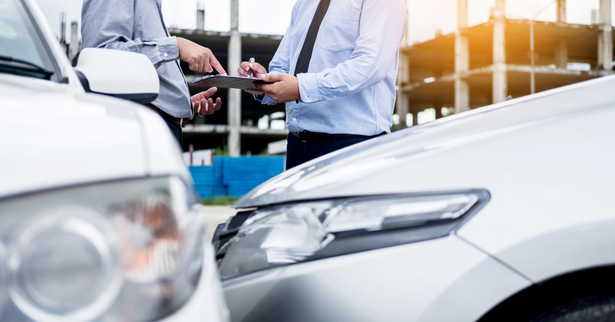 Two men, possibly legal professionals, stand by their cars discussing details while one holds a clipboard in front of a construction site in West Palm Beach.