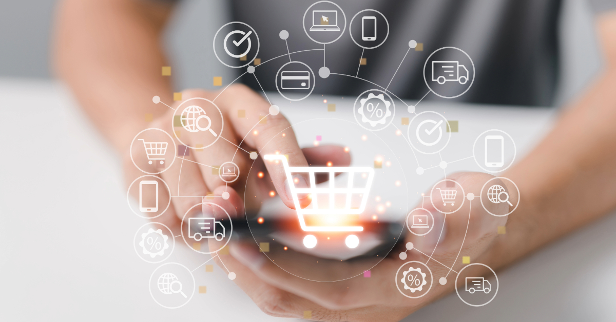 A man is holding a smartphone with a shopping cart on it, demonstrating the convenience of multi channel ecommerce software.