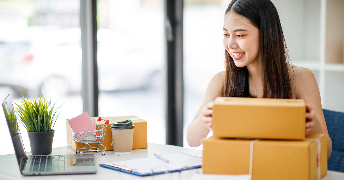 A woman supercharging e-commerce, sitting at a desk with boxes in front of her.