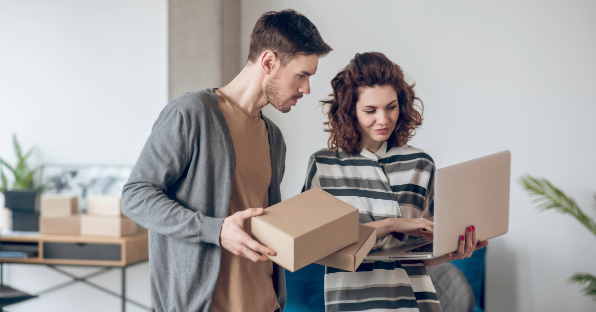A man and woman browsing an e-commerce website on a laptop in their new home, searching for products to sell.