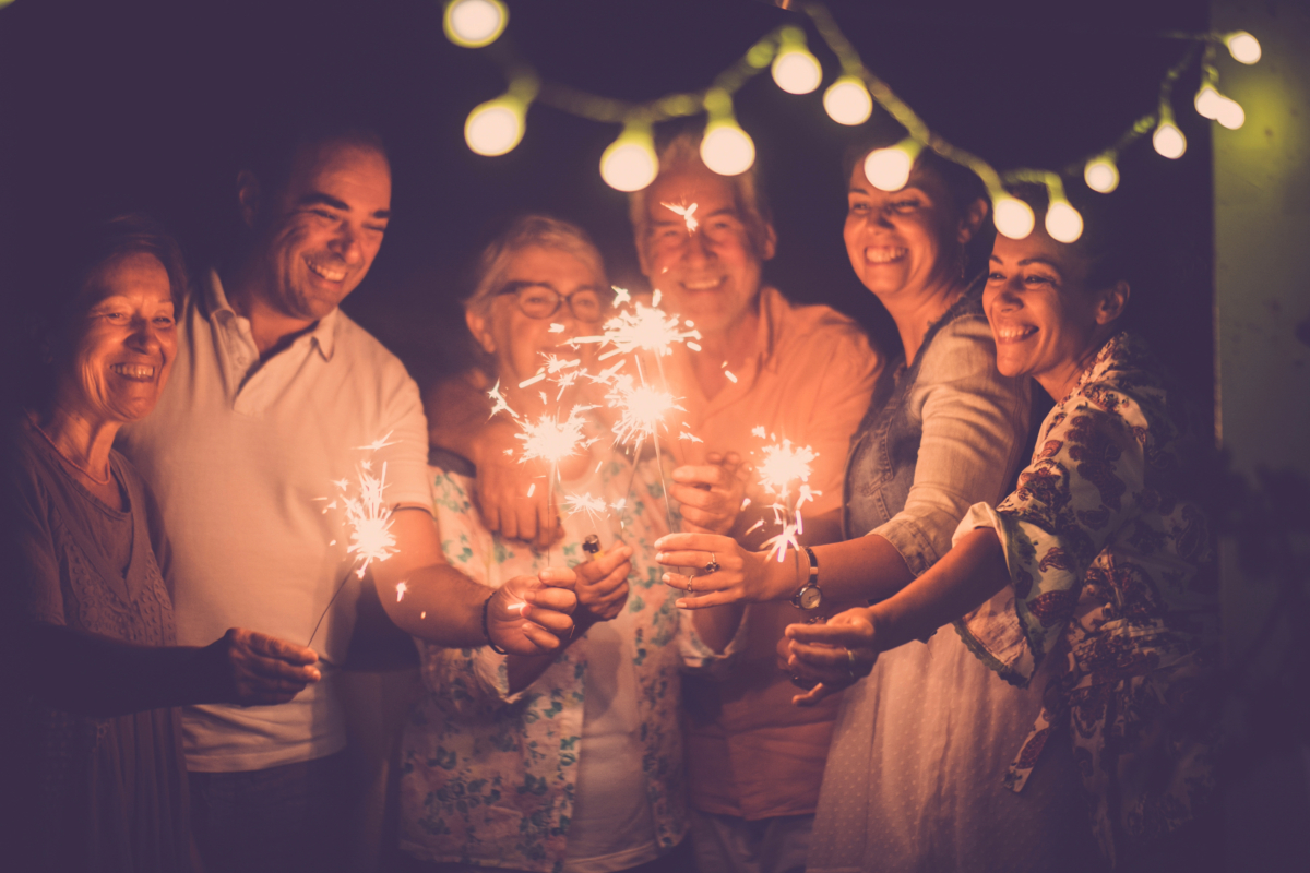 The happiness is palpable as a group of people celebrate the arrival of the new year, their faces illuminated by the glowing sparklers they hold.