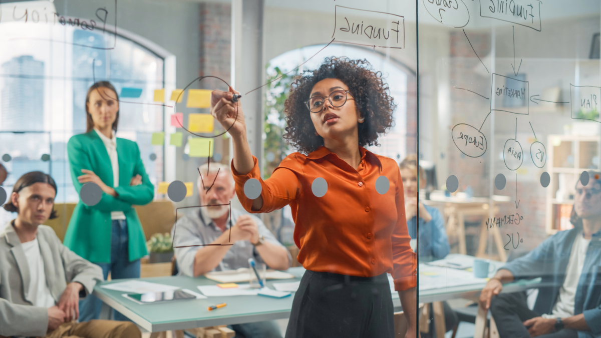 A group of people in a meeting room nourishes growth as they write on a board.
