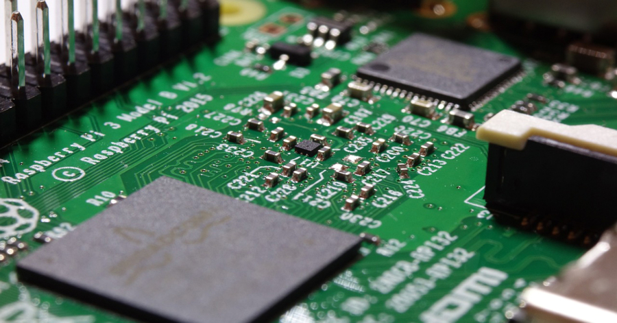 Close-up view of a green printed circuit board with various electronic components, including chips and resistors, labeled "Raspberry Pi 3 Model B V1.2." Ever wondered, "What is a Raspberry Pi used for?" This tiny computer powers an array of DIY projects.
