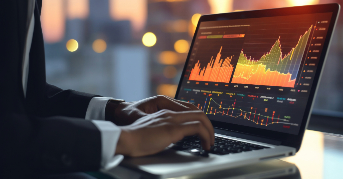Person typing on a laptop displaying colorful financial graphs and charts in a dimly lit office with city lights in the background, searching for tips for making money fast on cryptocurrency trading.
