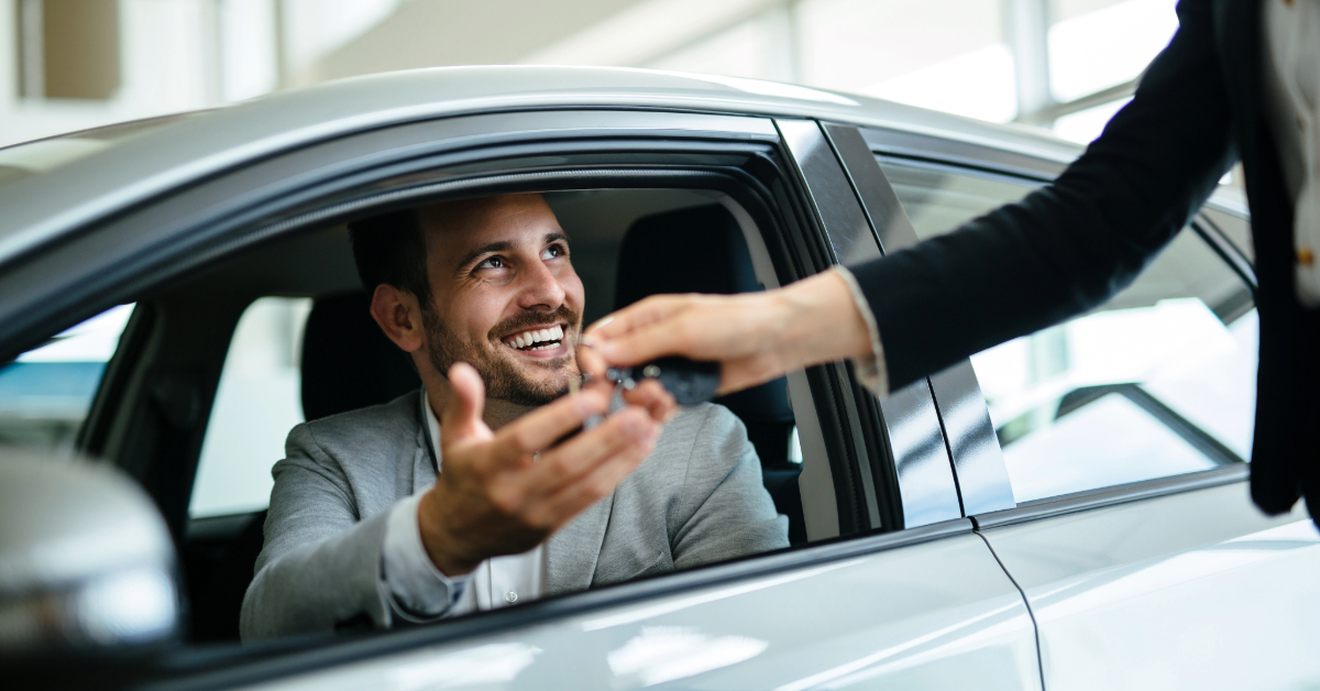 Inside an ideal vehicle, a person receives a set of keys from another individual outside, embodying the seamless Turo experience.