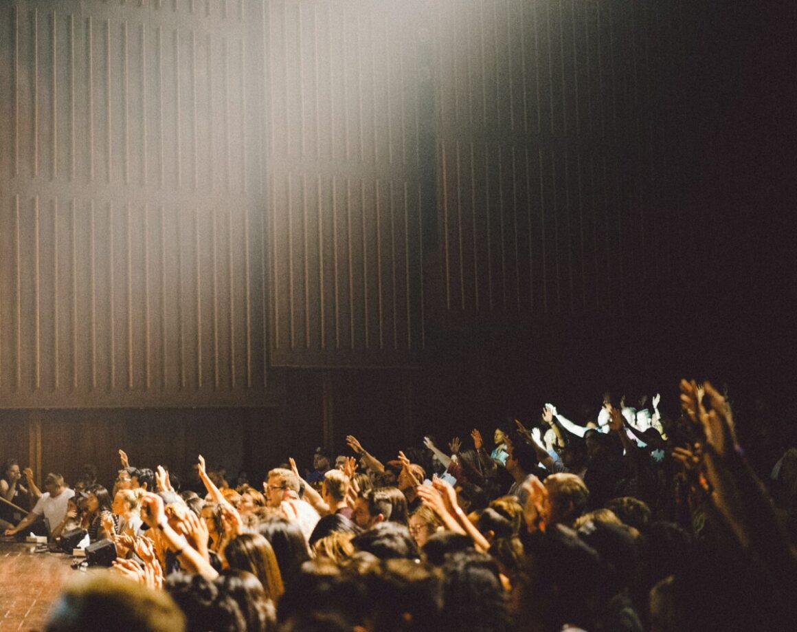 In a dimly lit auditorium, audience members raise their hands as discussions about the future of ecommerce unfold, driven by innovative DTC strategies.