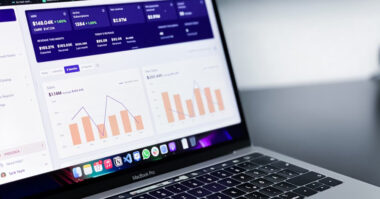 A laptop screen showcases graphs and data analytics, highlighting performance metrics and financial figures on a dark-themed interface—a testament to smart business moves and data-driven decision making.