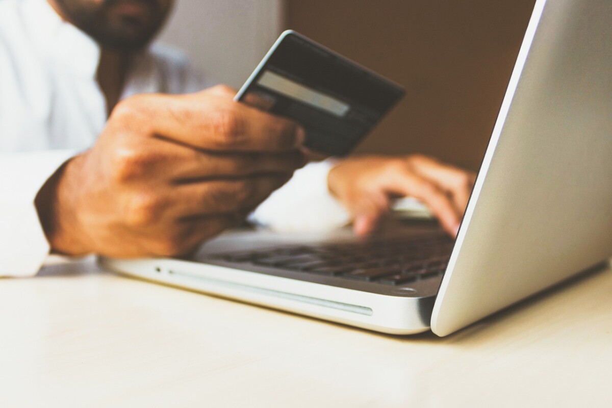 A person using a laptop and holding a credit card, illustrating an ecommerce transaction or DTC purchase through platforms like Shopify.