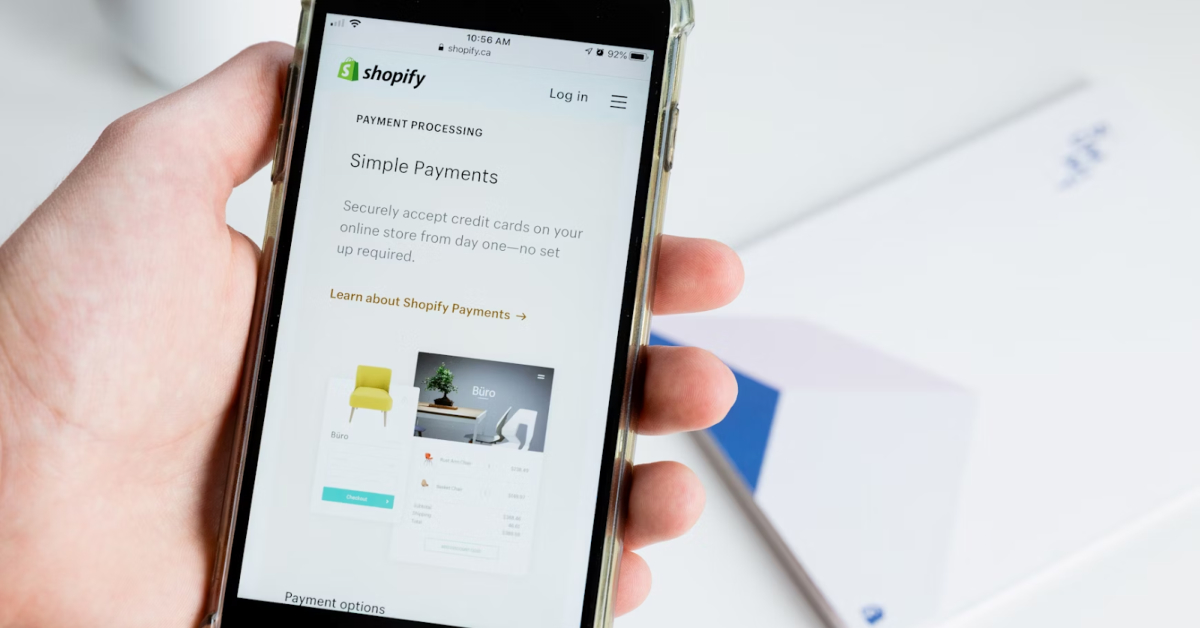 A person holds a smartphone showing a Shopify webpage titled "Simple Payments," highlighting online credit card processing features crucial for online retailers to manage sales and taxes efficiently.