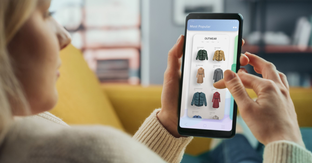 Person browsing ecommerce clothing options on a smartphone app while lounging on a couch.