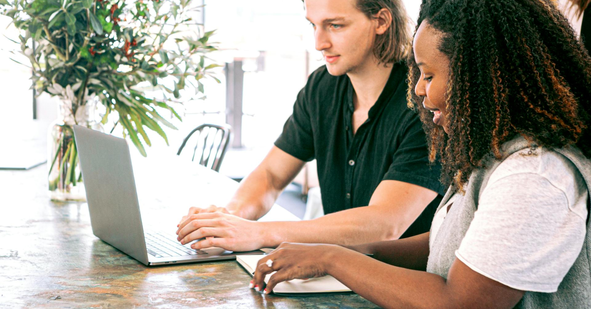 Two people diligently work on a laptop at a table adorned with a vase of flowers, focused on implementing best practices to enhance order fulfillment and reduce errors.